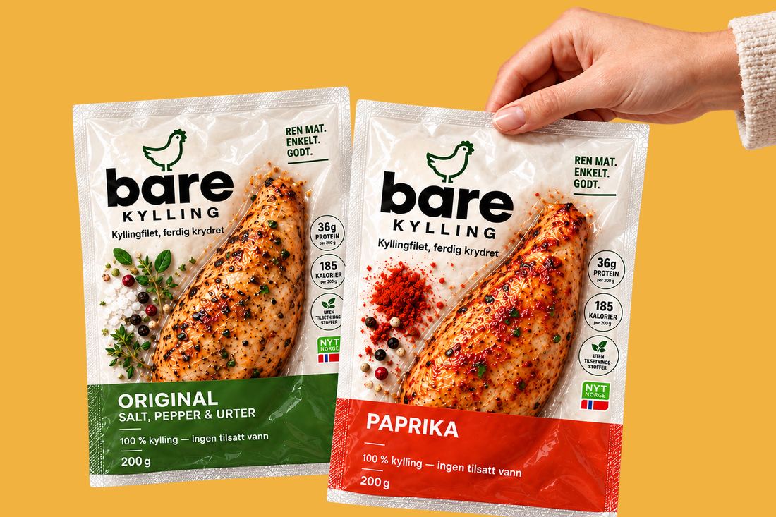 En hånd holder to pakker Bare Kylling: Original med grønn etikett og Sweet Paprika med rød etikett. Den krydrede kyllingfileten synes gjennom den klare emballasjen.